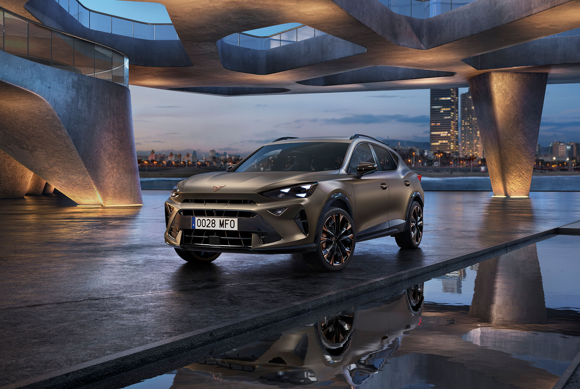 The 2024 Century bronze matt CUPRA Formentor parked on a reflective waterfront promenade. The sporty and aerodynamic new vehicle is positioned centre frame. The setting features futuristic architecture and Barcelona’s glowing city skyline at dusk.