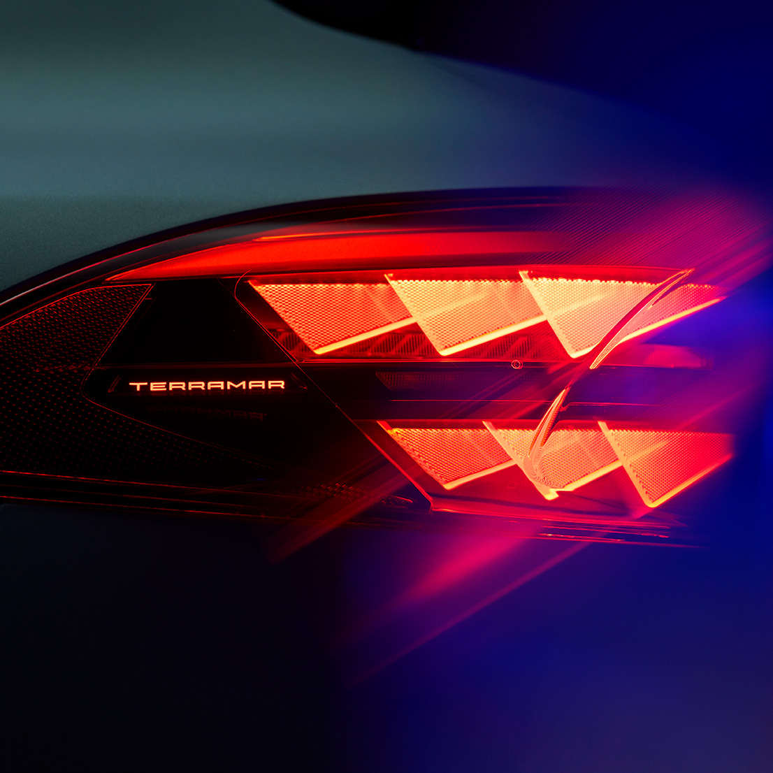 cupra terramar close-up of rear taillight with illuminated model name, showing distinctive red triangular light pattern against dark background