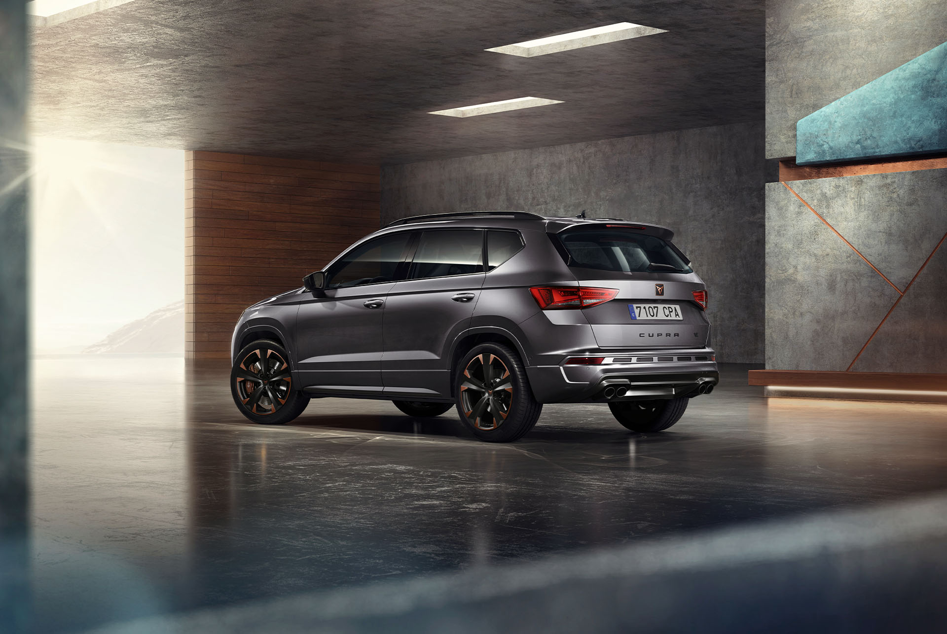 A grey cupra ateca suv displayed against a white background. The car features a bold front grille, led headlights and copper accent alloy wheels, highlighting its sporty car design.