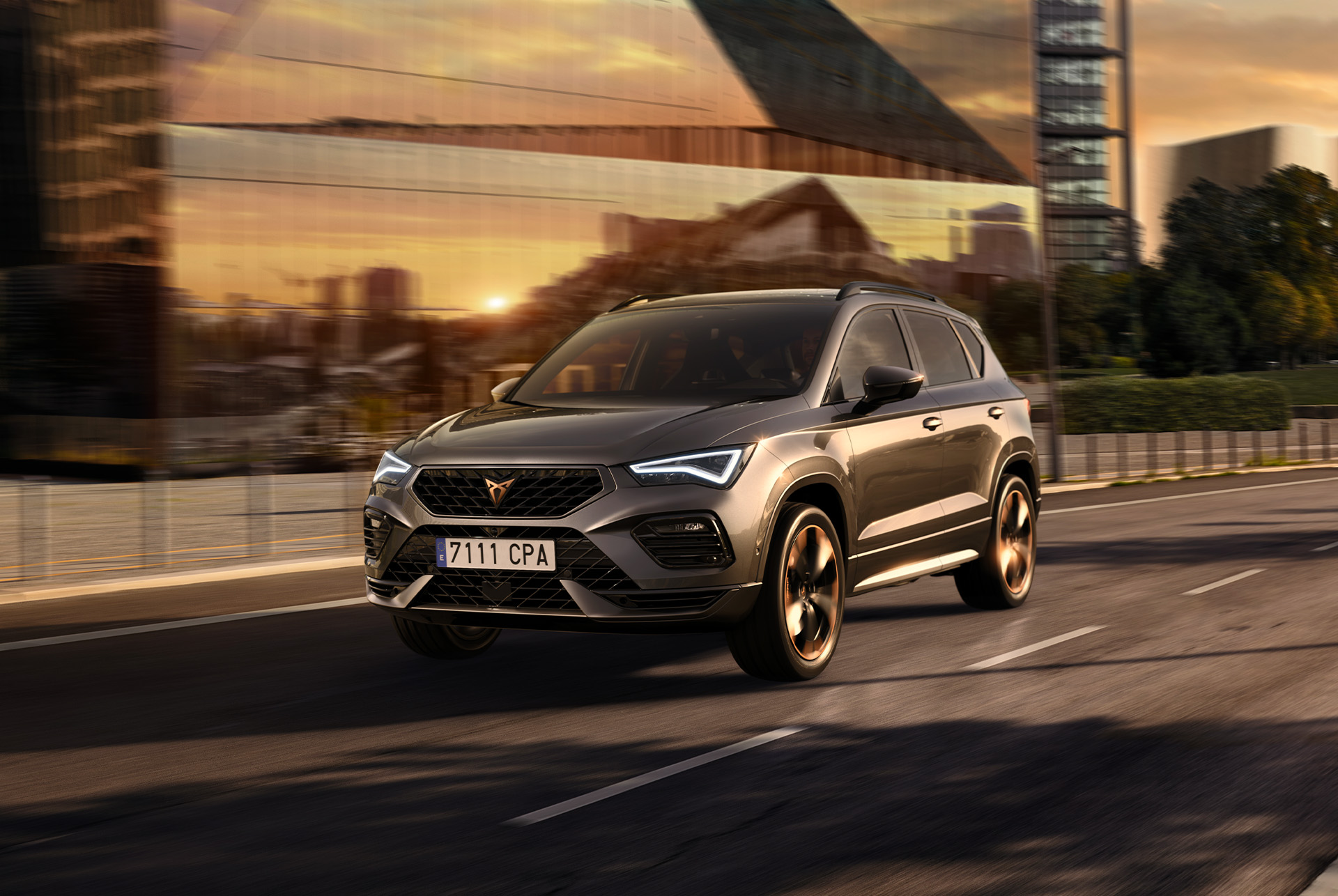 CUPRA Ateca SUV driving on a city road at sunset. The SUV is available with engines in 150hp and 190hp with 4-wheel drive, offering less emissions and fuel consumption.