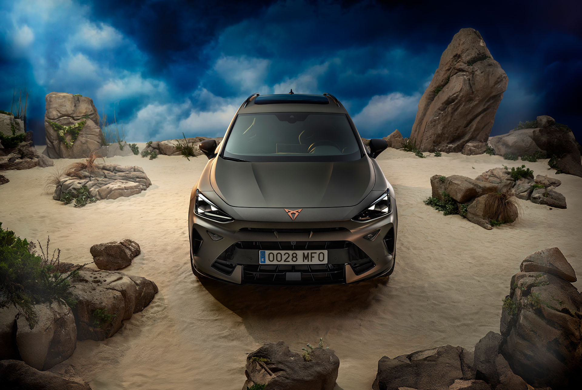 A CUPRA Formentor parked in the nature, showcasing its front in an angle view, surrounded by a sandy and rocky setting.