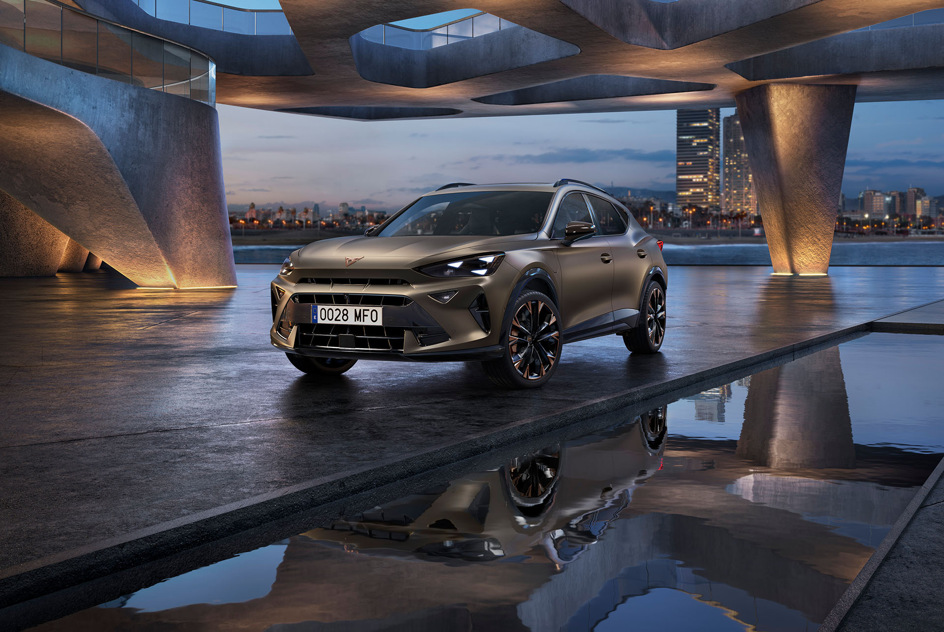 A CUPRA Formentor CUV 2024 technology. The car with copper accent wheels is parked under a curved concrete structure near a reflective water surface, with a twilight cityscape in the background featuring illuminated skyscrapers.