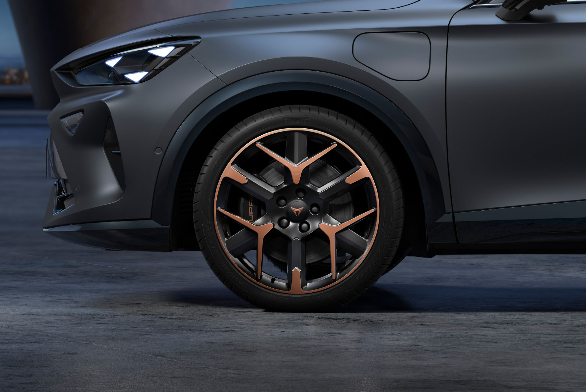 Front side view of left forged CUPRA copper and black car wheels, tyres and signature headlights.