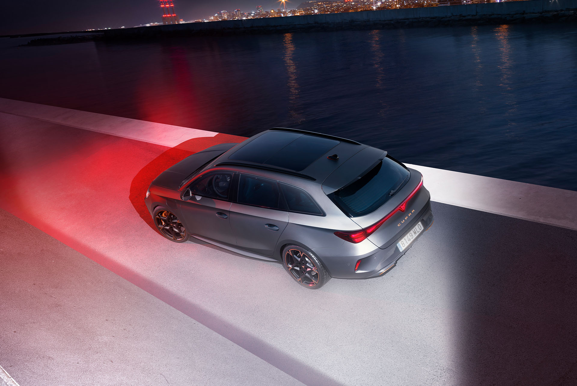 The image features a rear-side view of the CUPRA Leon Sportstourer  in sleek matte grey. Its sporty and aerodynamic design stands out at dusk, highlighting its modern and dynamic character.