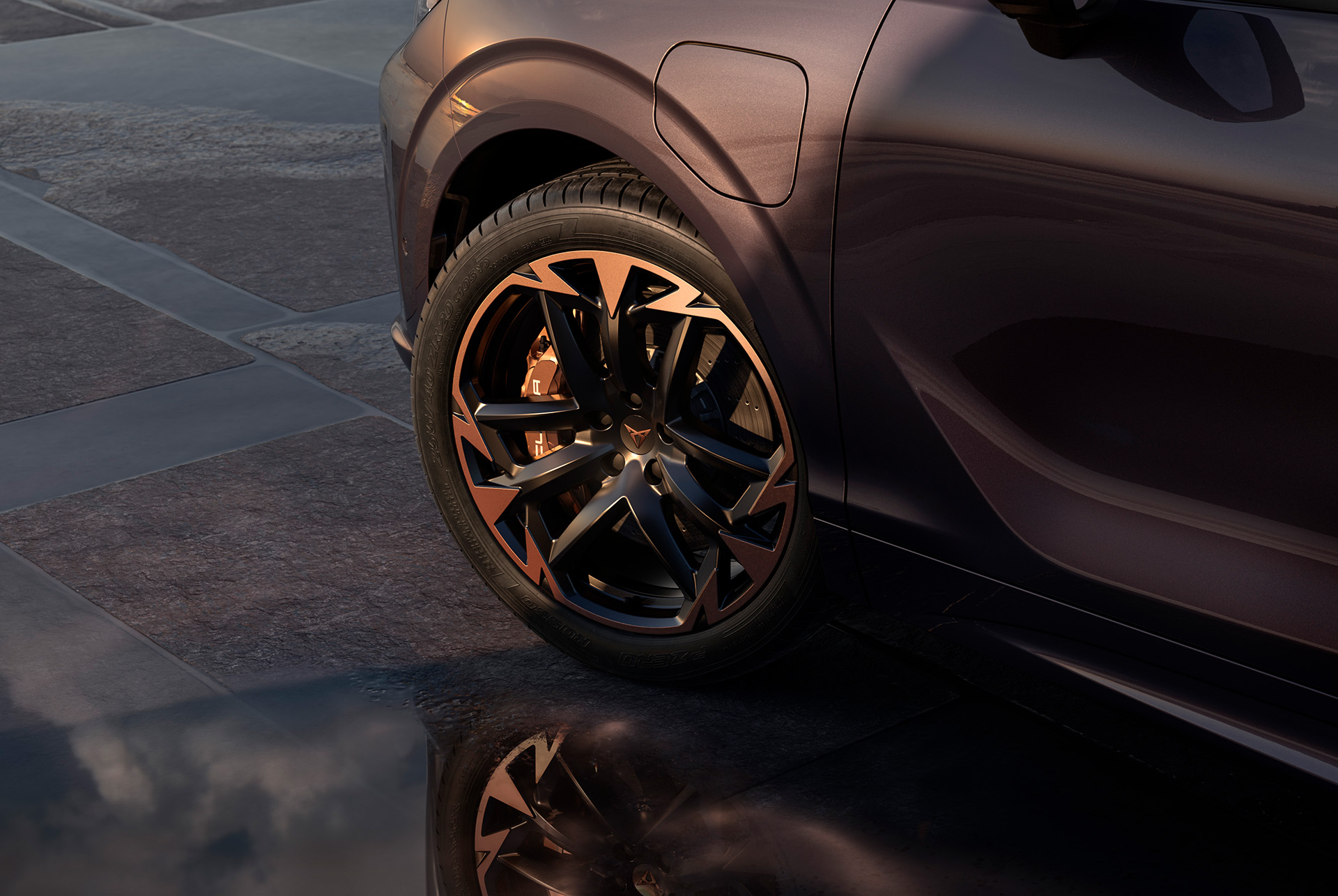 20 inch vortex copper alloy wheel on the new cupra terramar, in black with copper accents. Background includes a tiled pavement and part of the car's glossy, dark body.