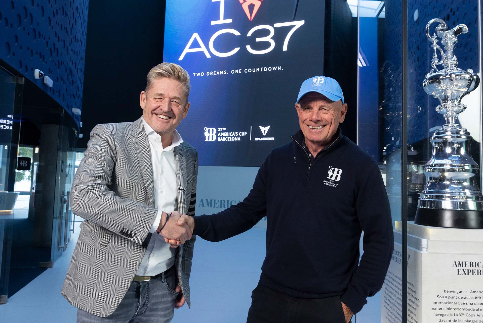 Ceo of cupra, wayne griffiths, shaking grant dalton's hand at the 37th america's cup in barcelona.