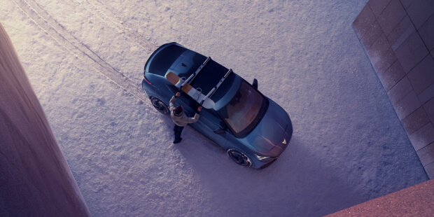 bev in the snow during winter months, cupra tavascan driver making adjustments to the roof rack in a snowy setting, birds eye view