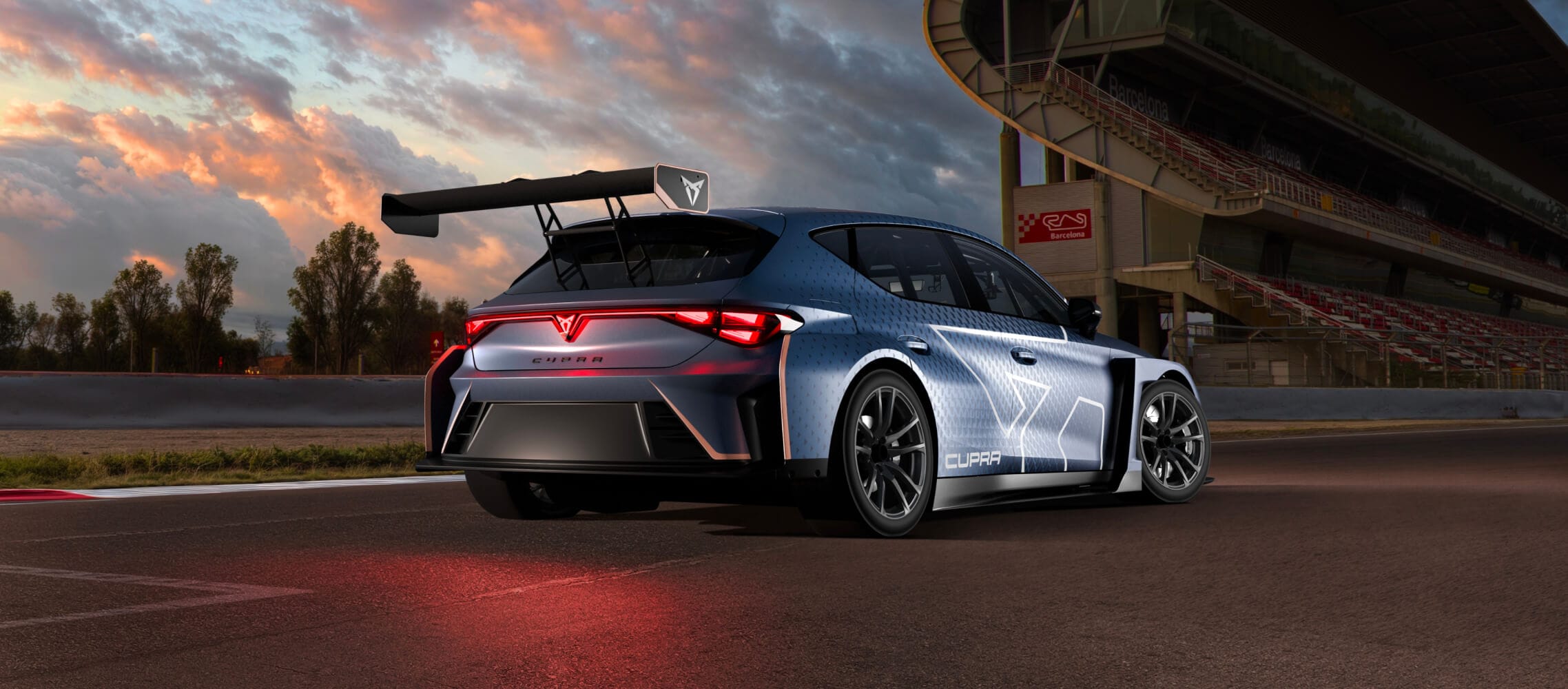 Rear view of the cupra leon vz tcr on the barcelona circuit track, highlighting the car’s aerodynamics, large rear wing and illuminated taillights under a dramatic sunset sky.